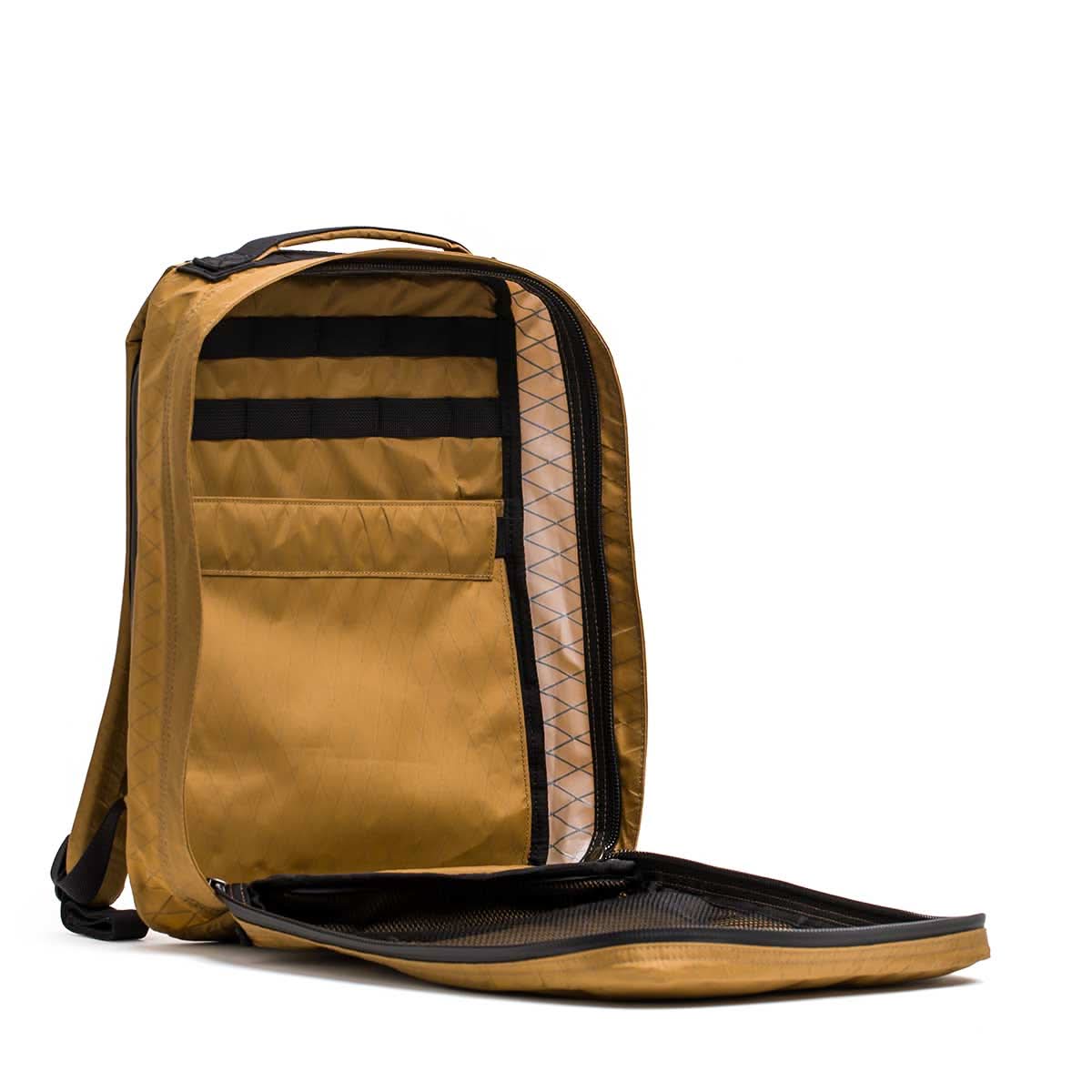 The GR0 - X-PAC is a tan, lightweight rucksack crafted from waterproof X-PAC material, with multiple interior pockets and a spacious, organized main compartment.