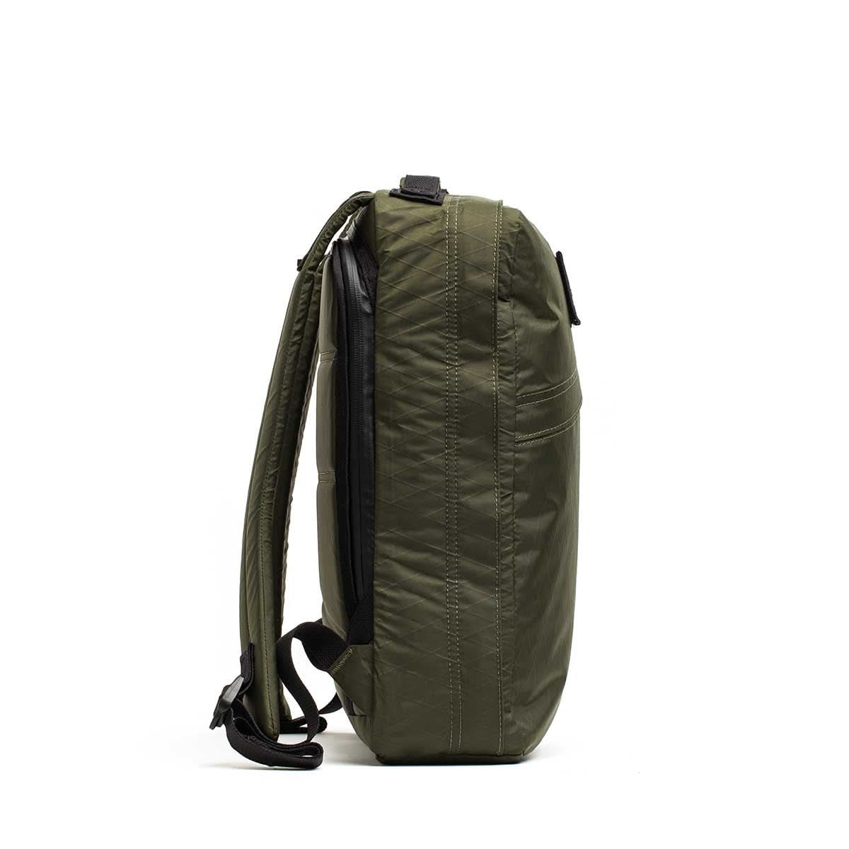 Side view of the GR0 - X-PAC olive green lightweight rucksack, made from waterproof material with padded shoulder straps, shown against a white background.