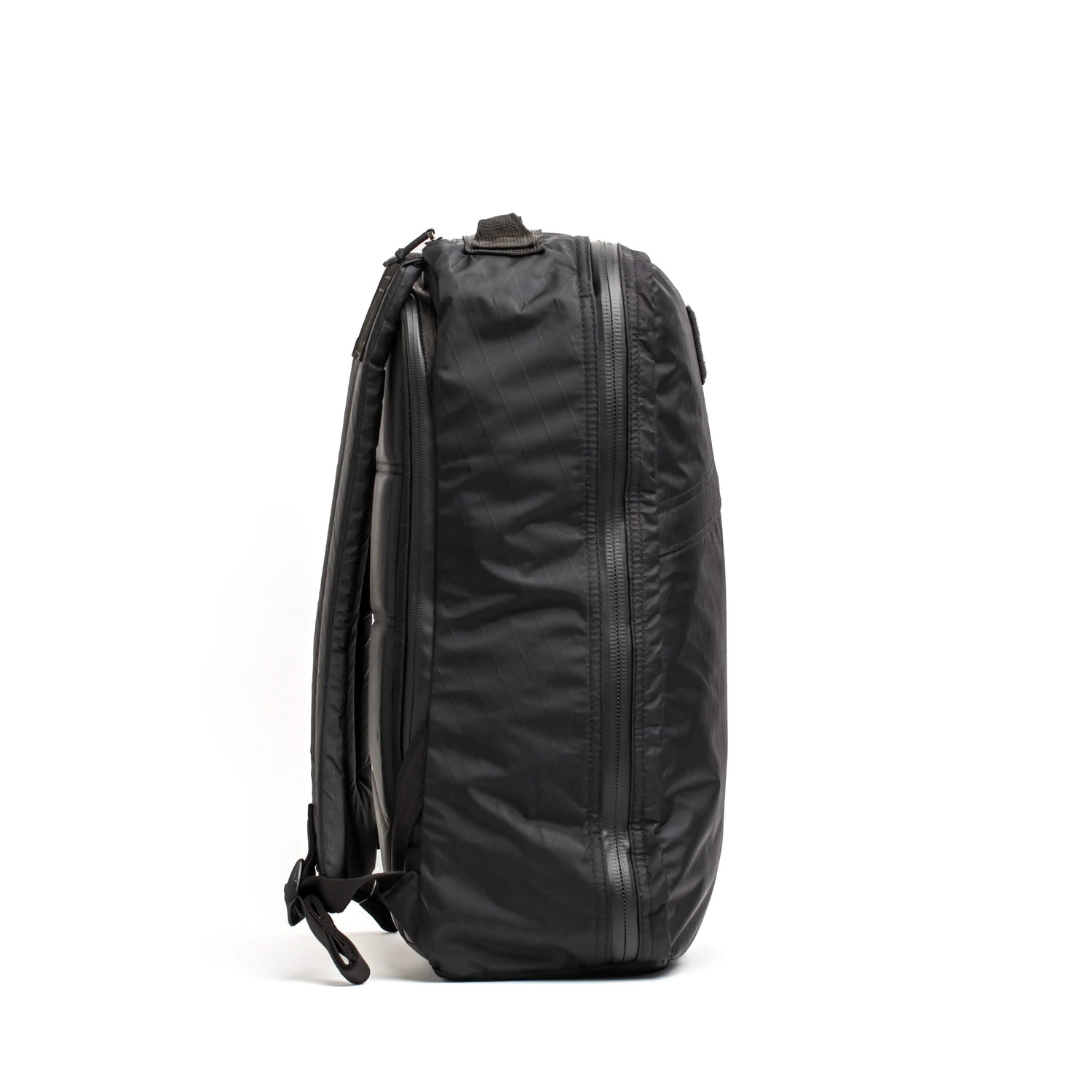 Side view of a black durable GORUCK backpack with multiple zippered compartments on white background