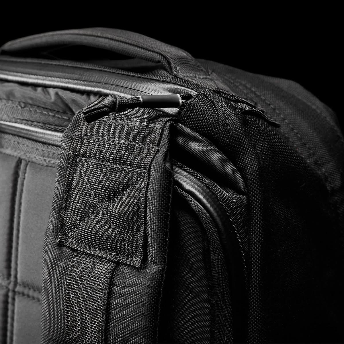 Close-up of a GR1 USA - Ballistic Nylon Cordura (The Original Ruck) 210D Back Panel’s stitched strap and zipper against a black background highlights this rucksack’s durability.