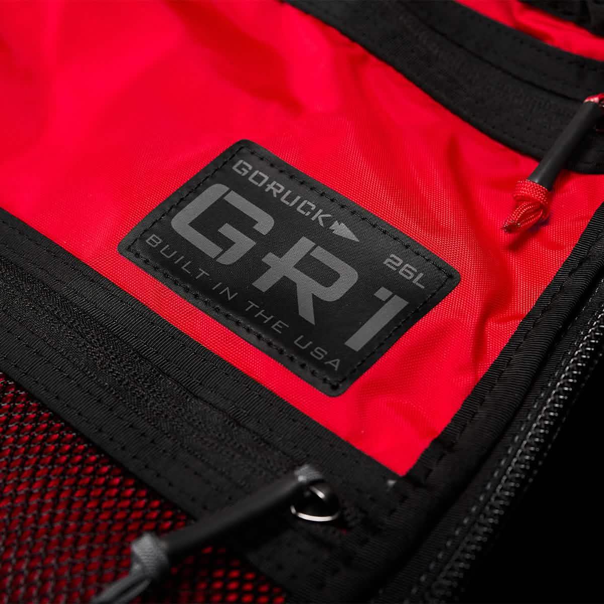 Close-up of red GORUCK GR1 military-style rucksack with black label and durable zipper