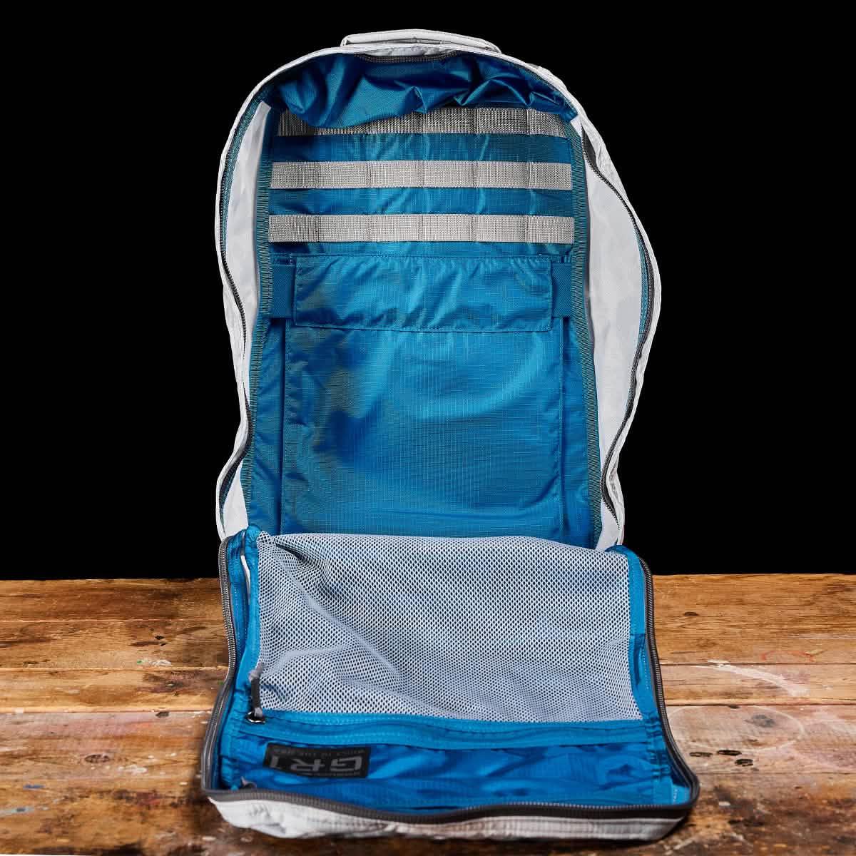 Open GORUCK rucksack with blue interior compartments and gray webbing on wooden surface