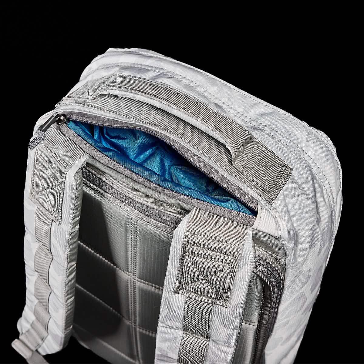 Close-up of white GORUCK rucksack straps and padded back panel with blue interior lining visible