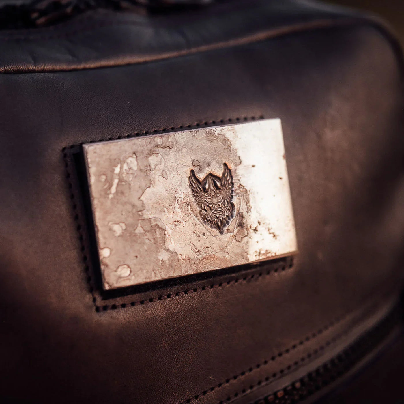 The GR1 USA x Carryology - Berserker Viking features a metal wolf head badge inspired by Viking armor, displayed on black leather—perfect for your bag or jacket.