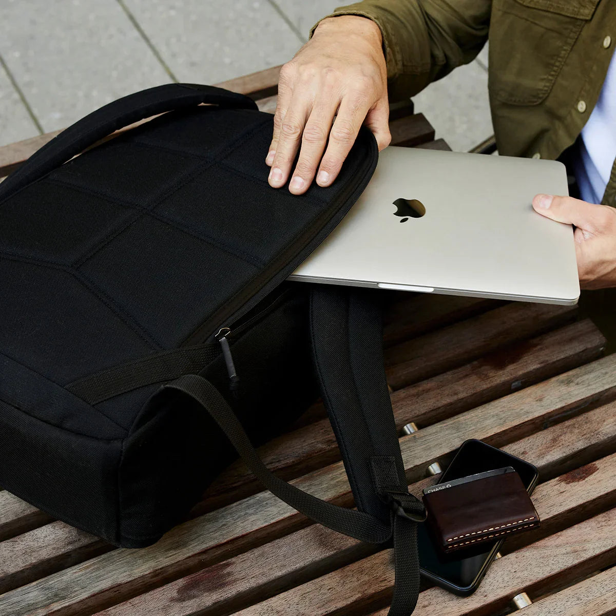 Placing your MacBook into the GR1 USA Slick - Ballistic Nylon Cordura backpack with a bombproof laptop compartment, phone and wallet nearby—built with Special Forces-grade quality for daily adventures.