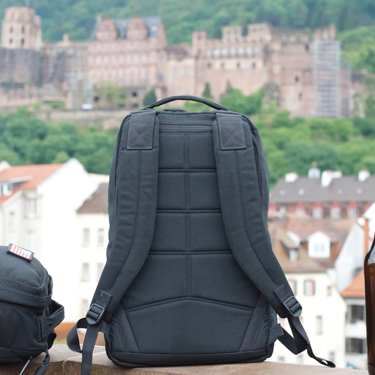 Back view of a sturdy black GORUCK rucking backpack with padded straps on a city rooftop background