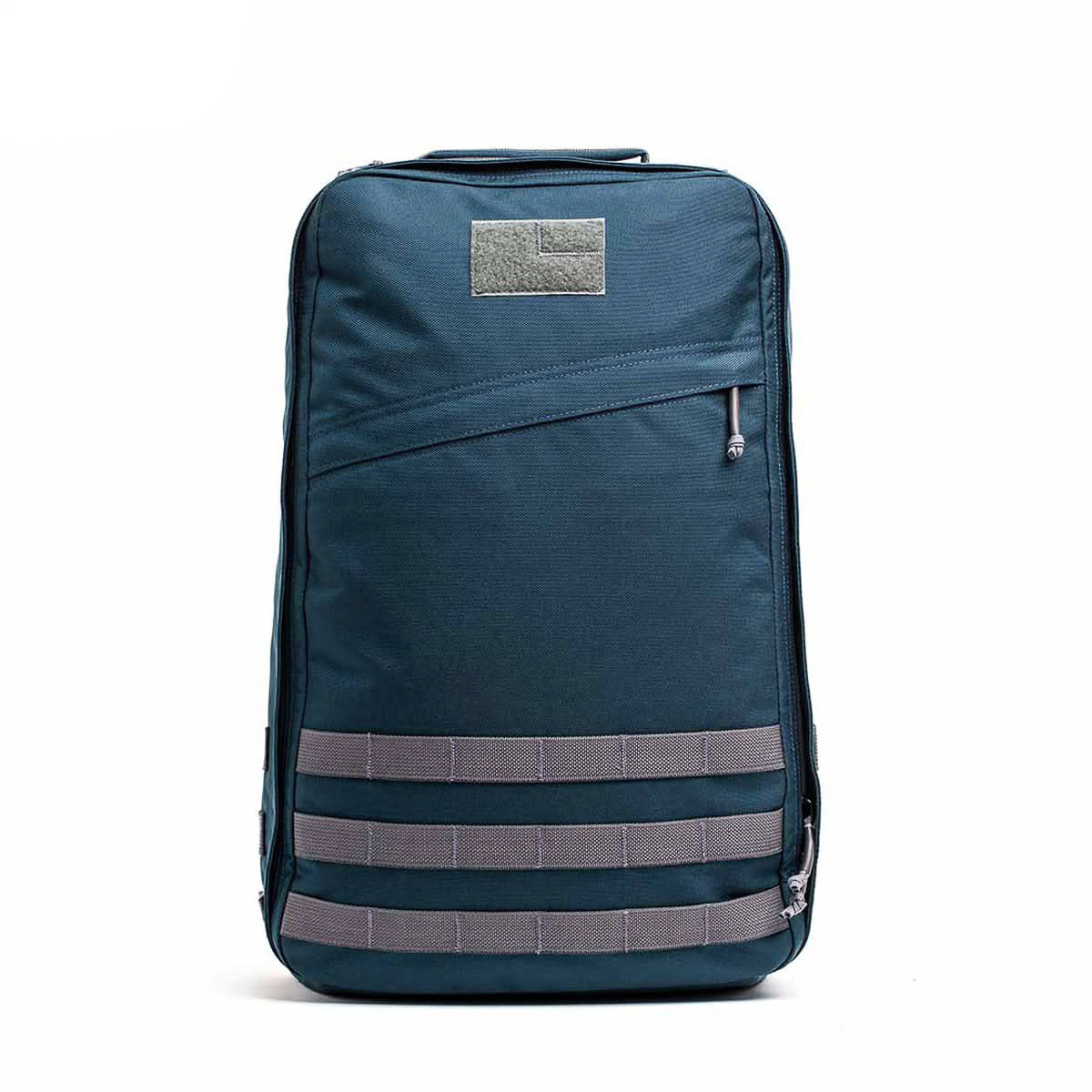 A GR1 USA - Cordura rucksack in blue with grey straps and a front zipper pocket, standing upright on a white background.