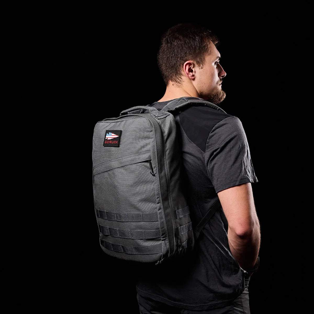 Man wearing GORUCK Wolf Grey rucksack backpack against black background