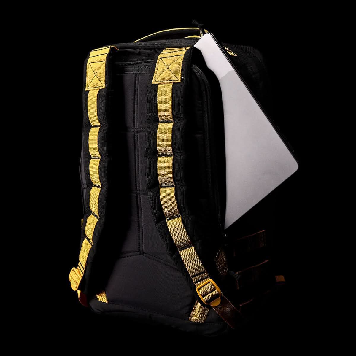 The GORUCK GR1 USA - Cordura (The Original Ruck) is a black rucksack with yellow straps, boasting a Special Forces-grade design and a bombproof laptop compartment, set against a black backdrop.