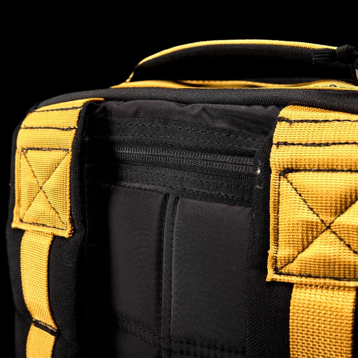 Close-up of the durable GR1 USA - Cordura rucksack by GORUCK, featuring yellow straps and stitching against a black background, designed to meet Special Forces ruggedness.