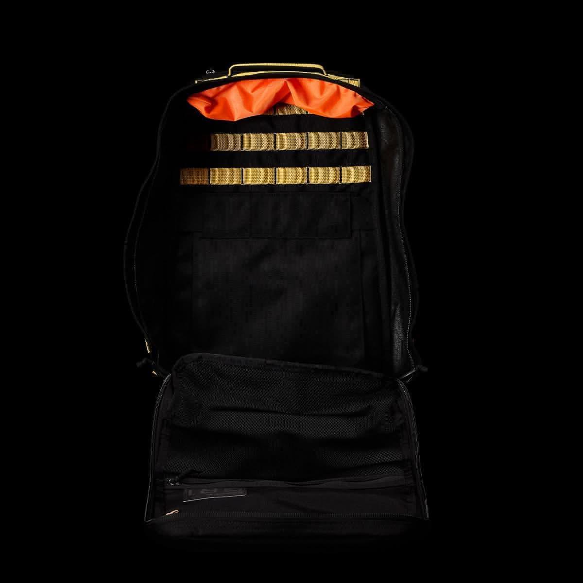 Open black GORUCK rucksack showing interior organization with tan webbing and bright orange lining