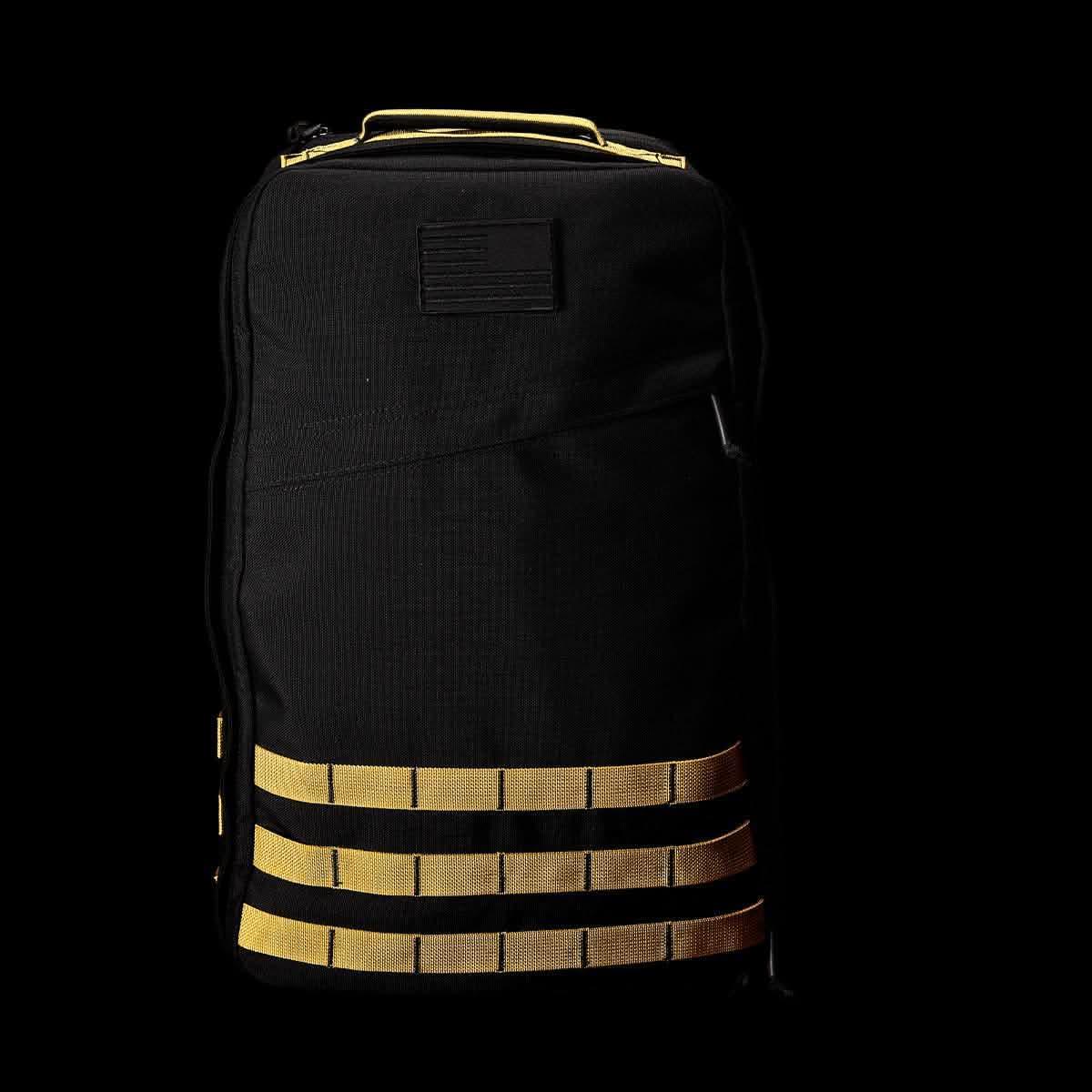 Black tactical rucksack with gold MOLLE webbing and a subdued American flag patch on front