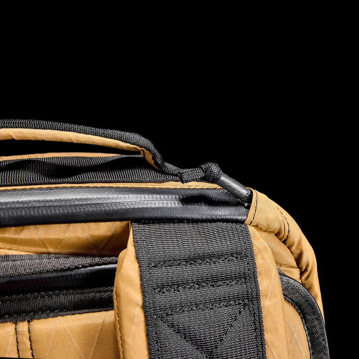 Close-up of coyote brown GORUCK backpack handle and black webbing strap with detailed stitching