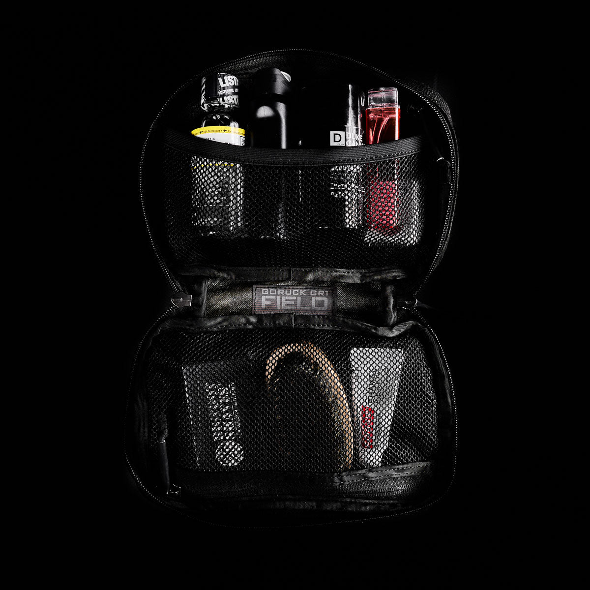 The GR1 Field Pocket, shown open on a dark background, is a black dopp kit with mesh pockets—perfect for grooming essentials, hygiene items, or organizing electronics.