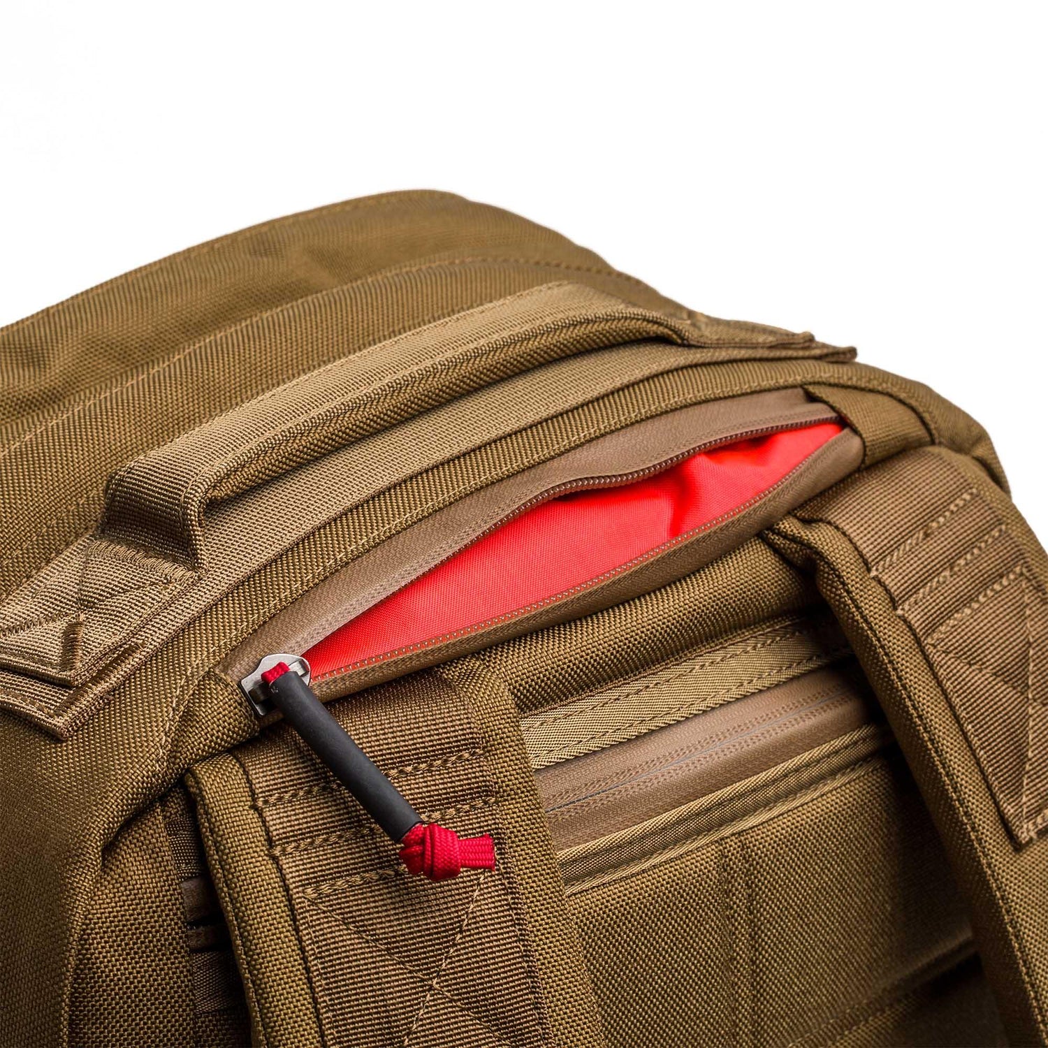 Close-up of the GR2 - Cordura in brown with a partially open zipper, showing its bright red interior pocket—ideal for anyone seeking a Special Forces-grade backpack or a dependable carry-on travel bag.