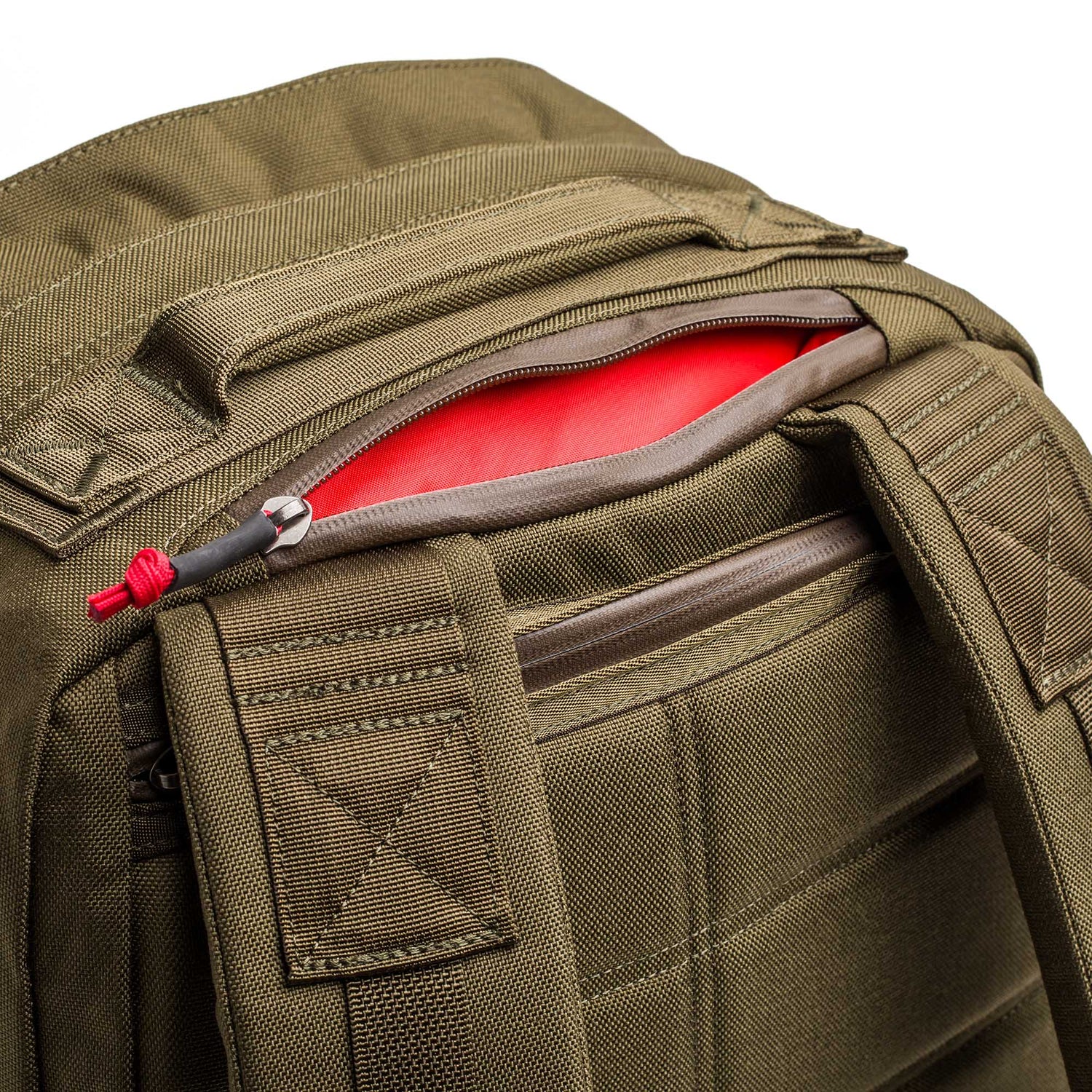 Close-up of an olive green GR2 - Cordura rucksack with a red item partially visible in an open zipper pocket.