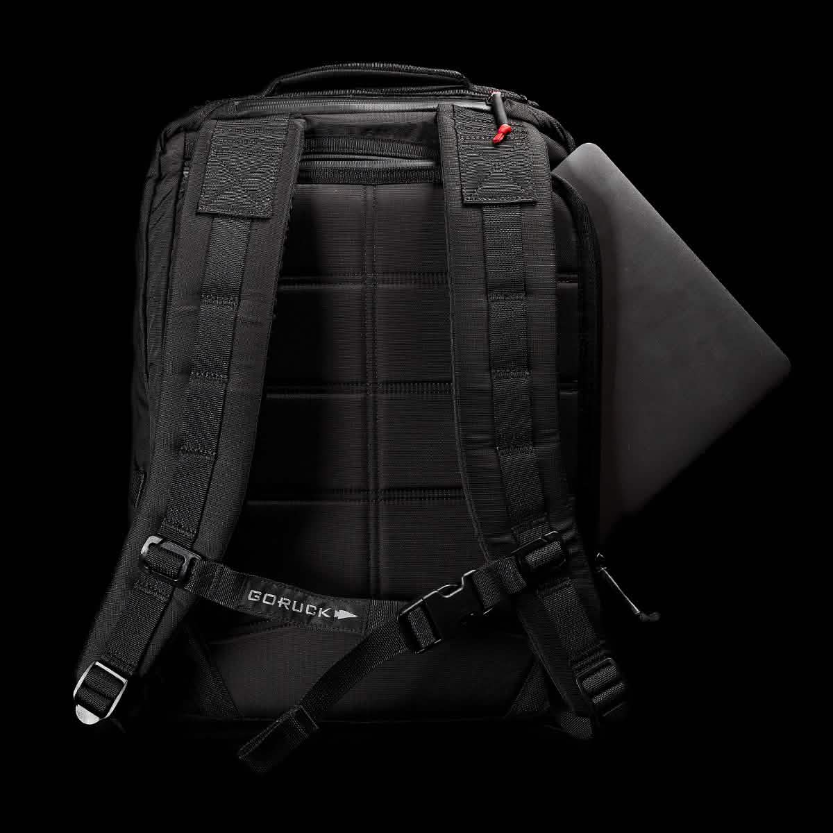 The GORUCK GR2 – Ripstop ROBIC® is displayed against a dark background. This water-resistant rucksack, crafted from durable material, features padded shoulder straps. A laptop is partially visible, being slid into its main compartment.