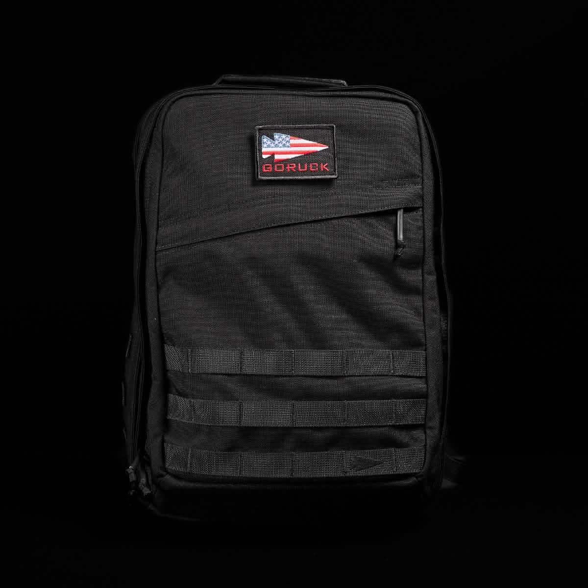 Black GORUCK rucksack with American flag patch, rugged tactical design against black background
