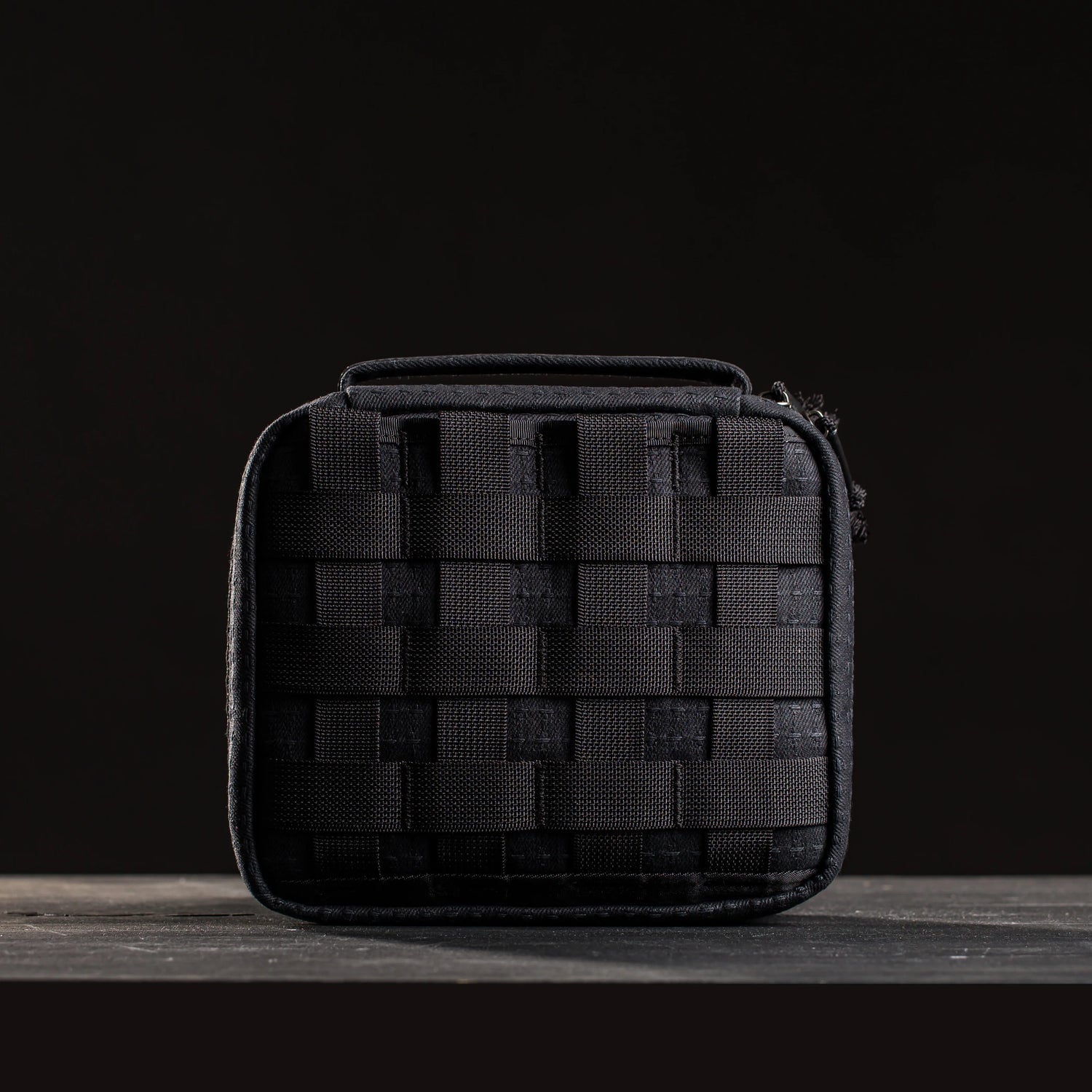 Black tactical GORUCK field pocket pouch with heavy-duty webbing on dark wood surface