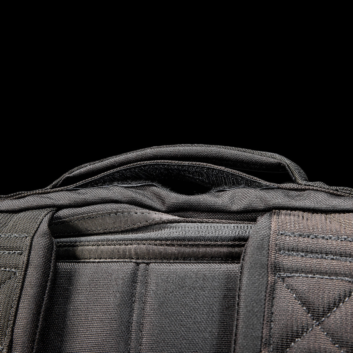 Close-up of the GR2 USA Throwback backpack handle and padded shoulder straps, made from rugged 1000D Cordura, shown against a black background.