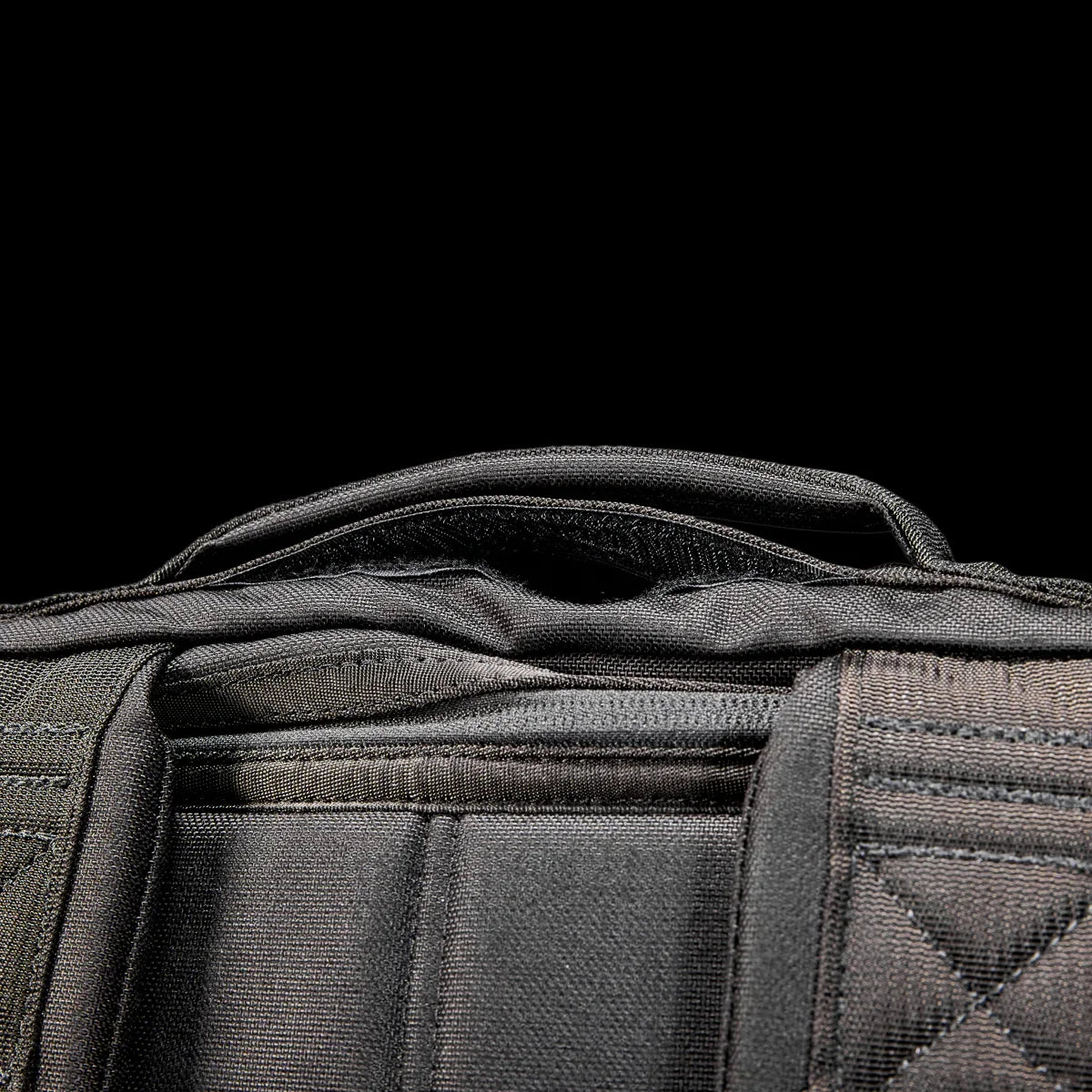 Close-up of black GORUCK backpack handle and durable stitching on rugged rucking gear against black background