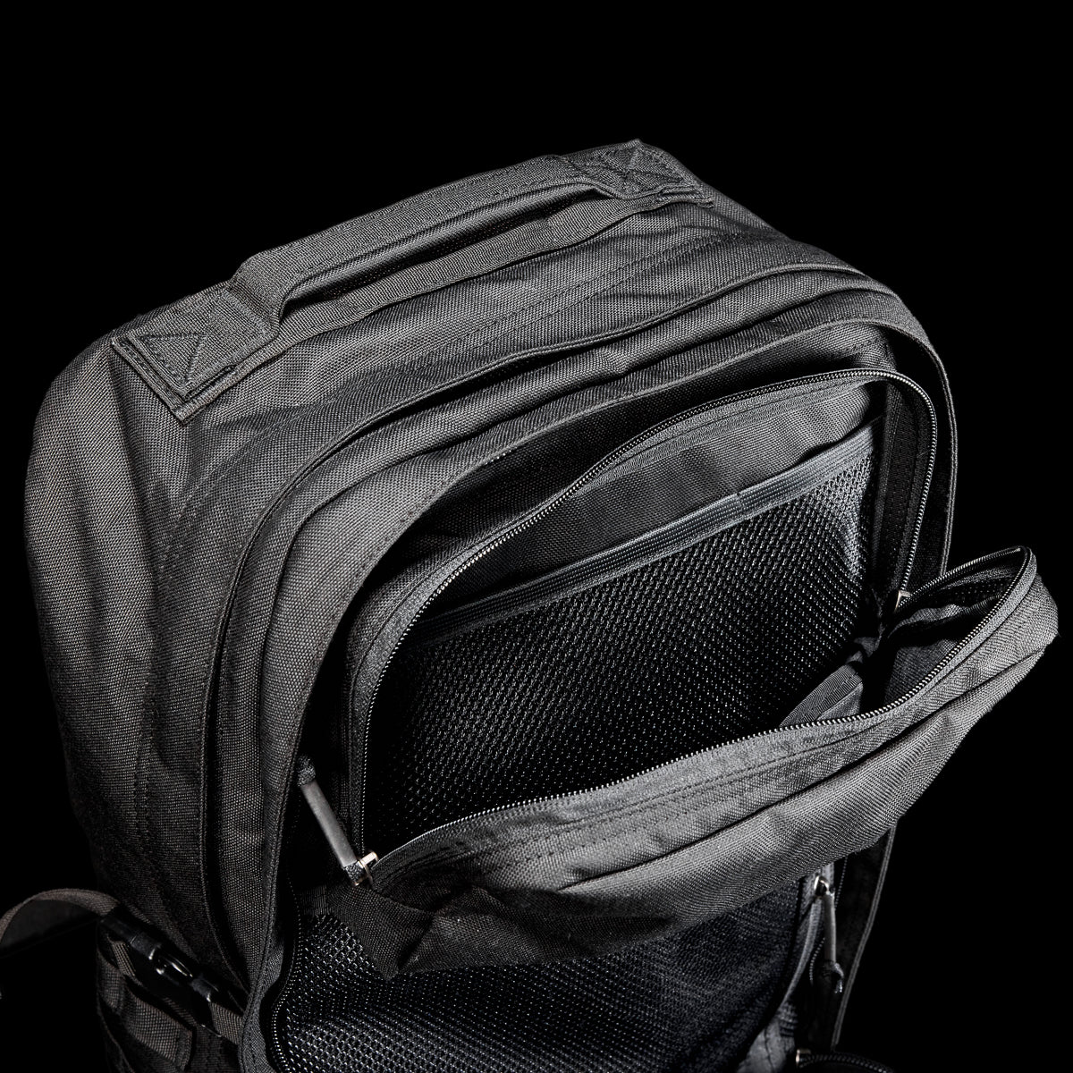 The GR2 USA Throwback travel backpack in black, made from durable 1000D Cordura with unzipped compartments and a mesh pocket, is displayed against a solid black background.