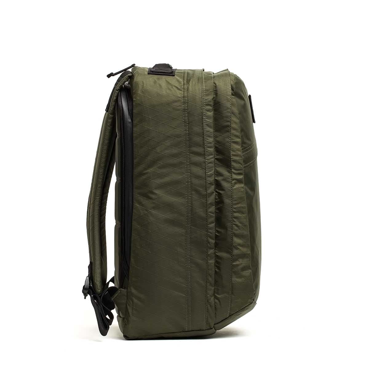 Side view of a green GR2 X-PAC backpack featuring black AquaGuard zippers and straps, standing upright against a white background.