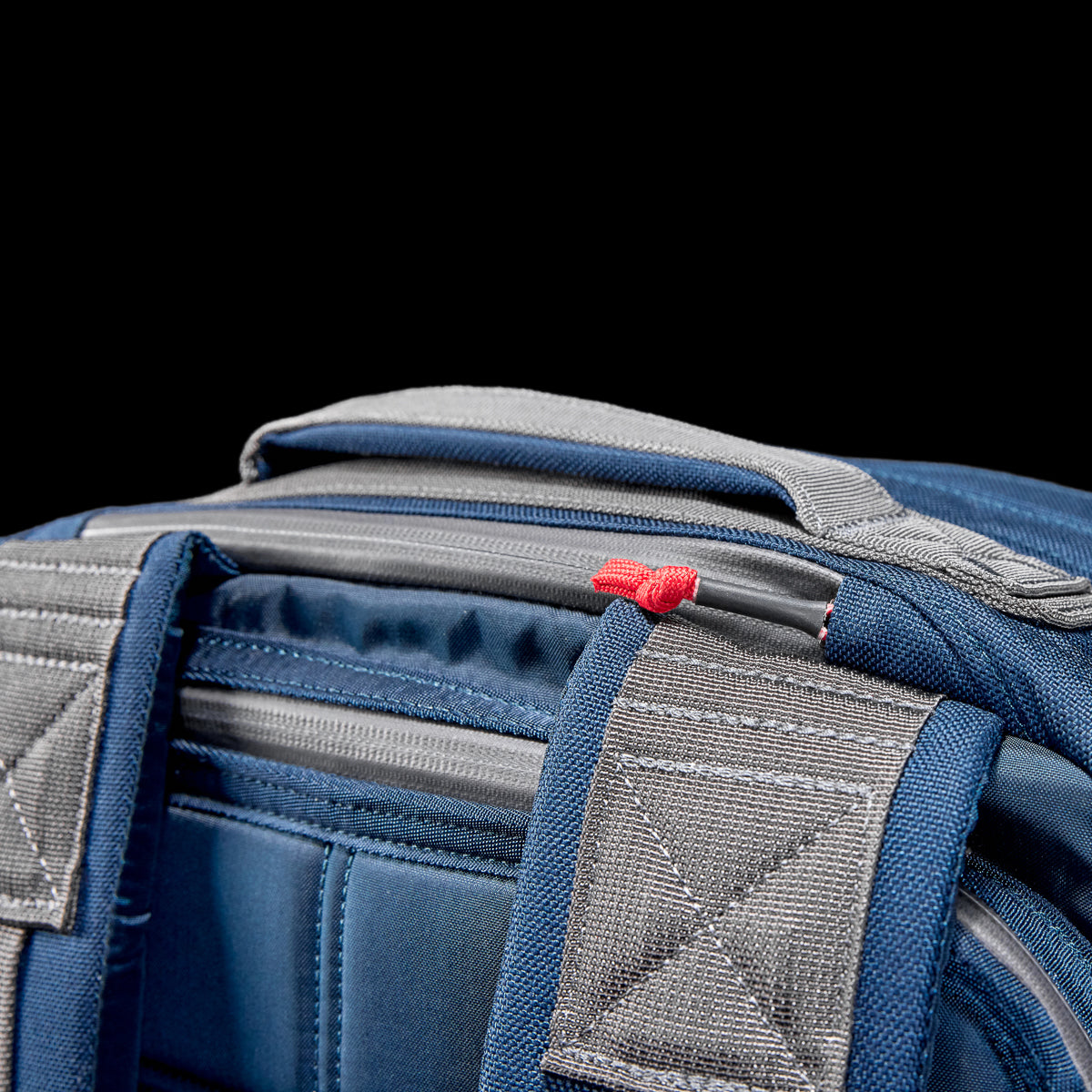 Close-up of the blue GR2 Cordura backpack, favored by Special Forces, featuring padded straps and a red zipper pull on a black background.