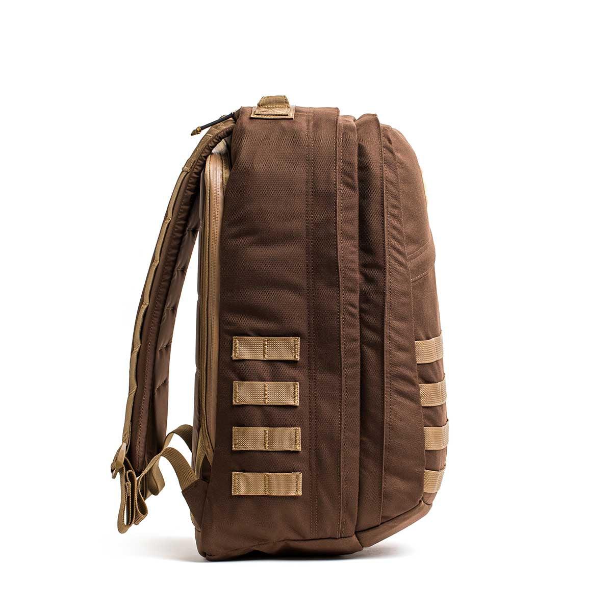 Side view of a durable brown GORUCK rucksack with padded straps and coyote-colored accents