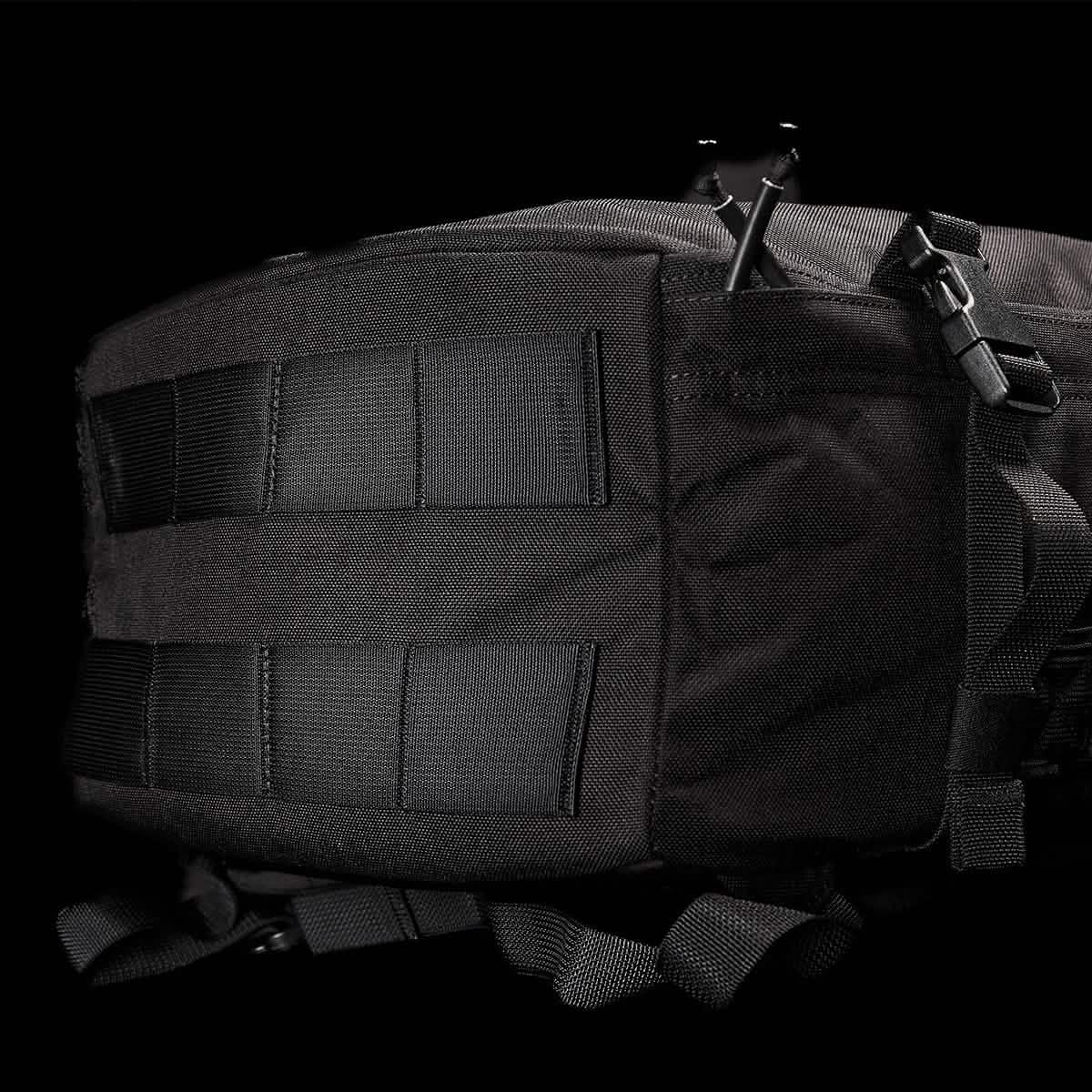 Close-up of black GORUCK rucksack showing tactical straps, durable fabric, and buckle against black background