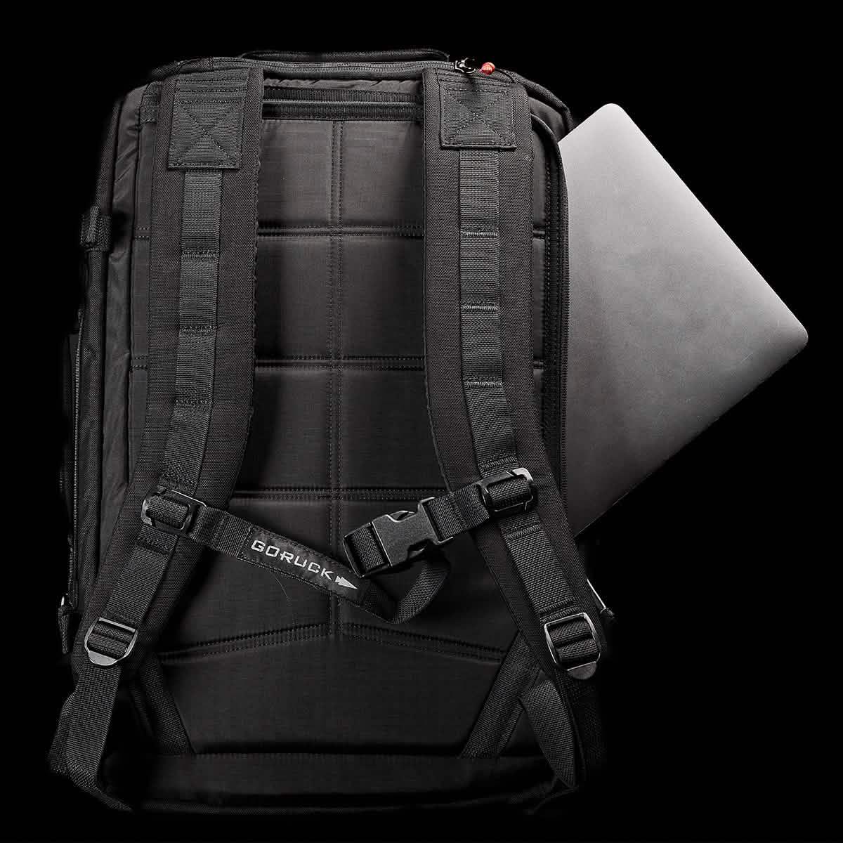 Black GORUCK rucksack back view with padded shoulder straps and a laptop partially inserted
