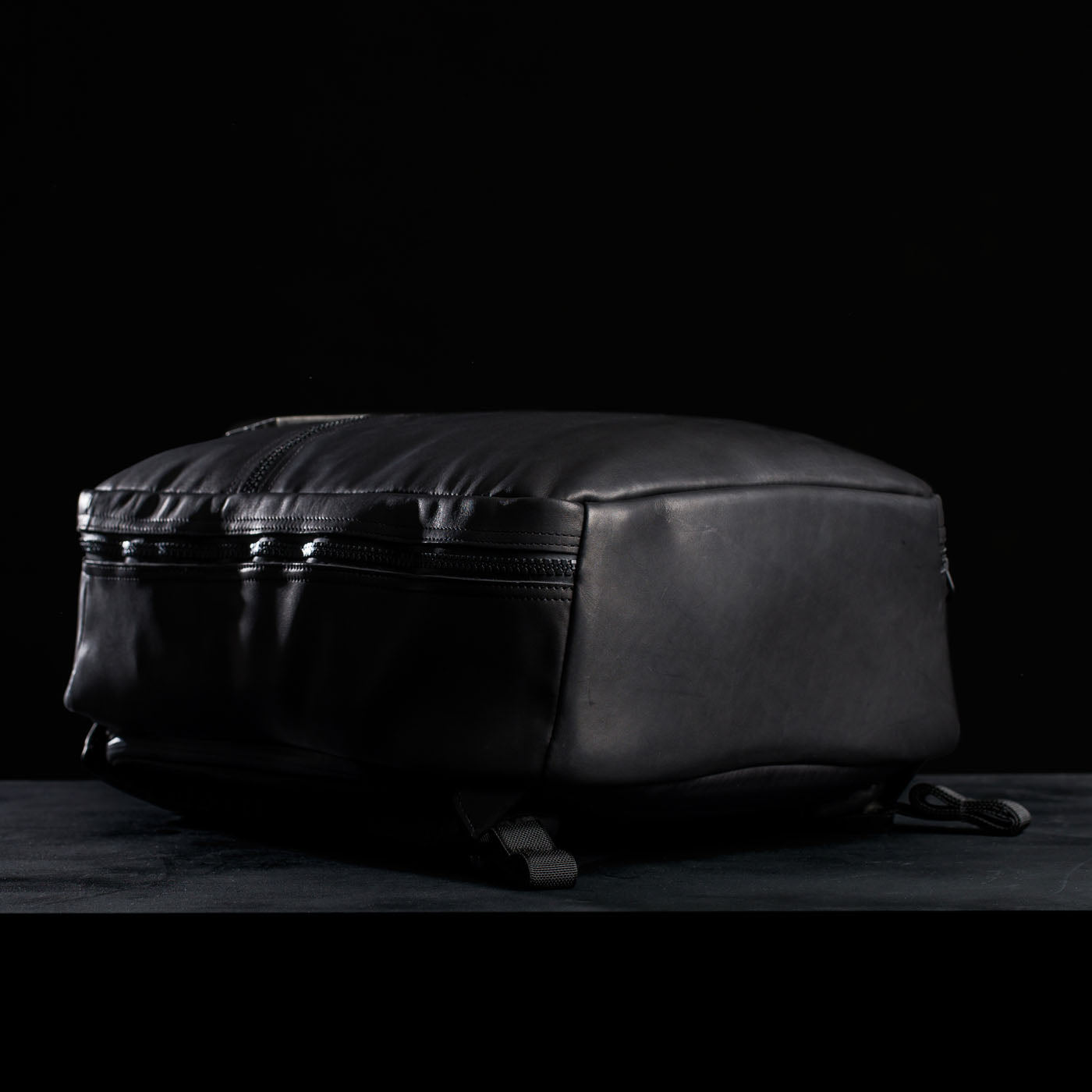 A black GR1 USA x Carryology - Berserker Viking backpack with zippered pockets lies flat against a dark background.