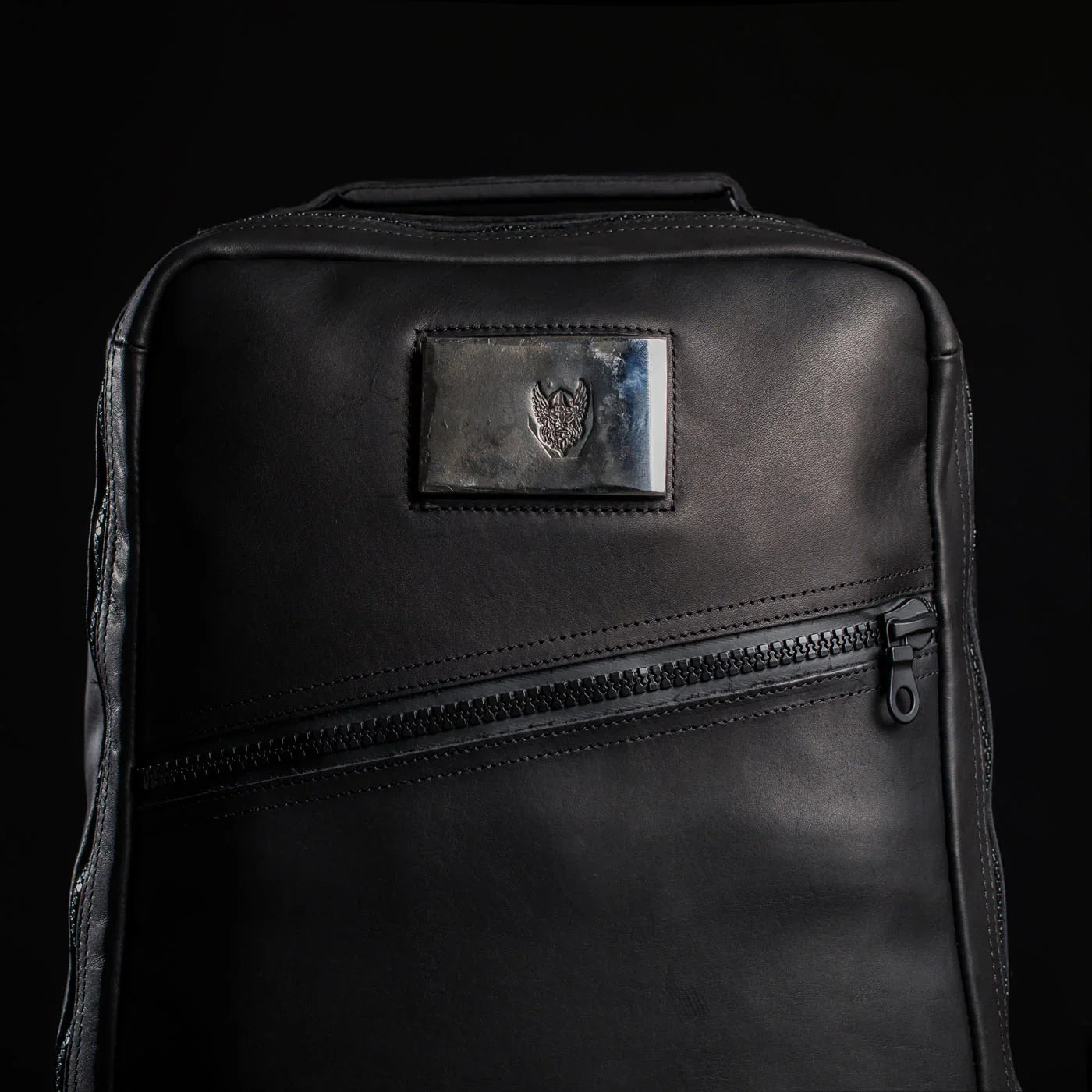 Black leather GORUCK backpack with diagonal zipper and metal plate featuring Viking logo on front