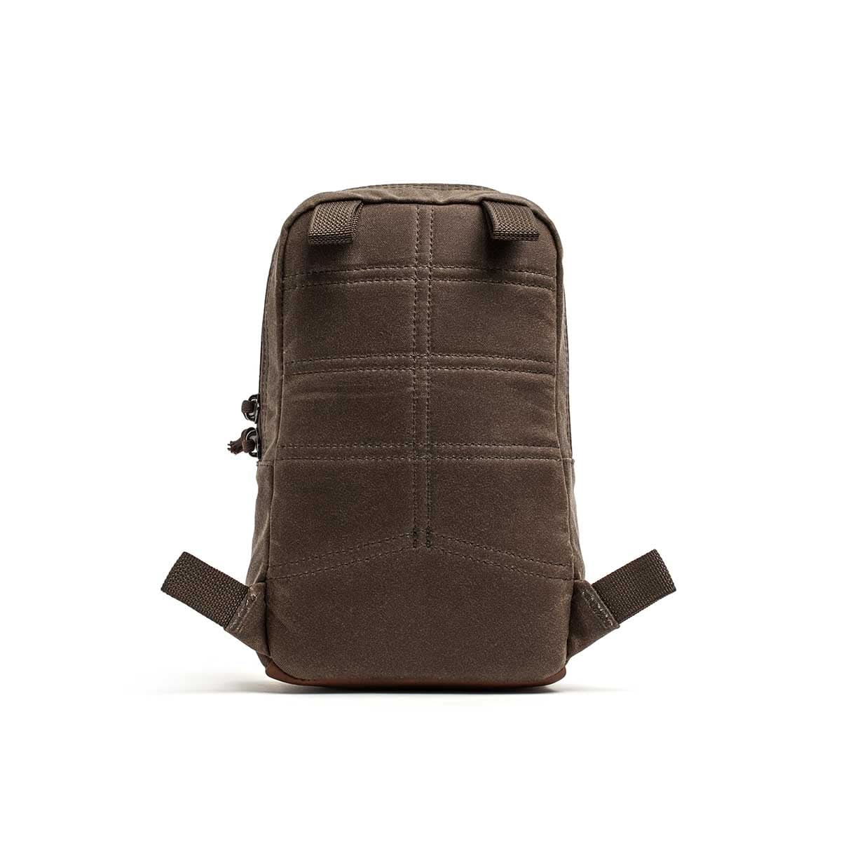 The Waxed Canvas GRenade is a small, brown rectangular ruck made from durable waxed canvas with visible stitching and two side straps, displayed on a white background.