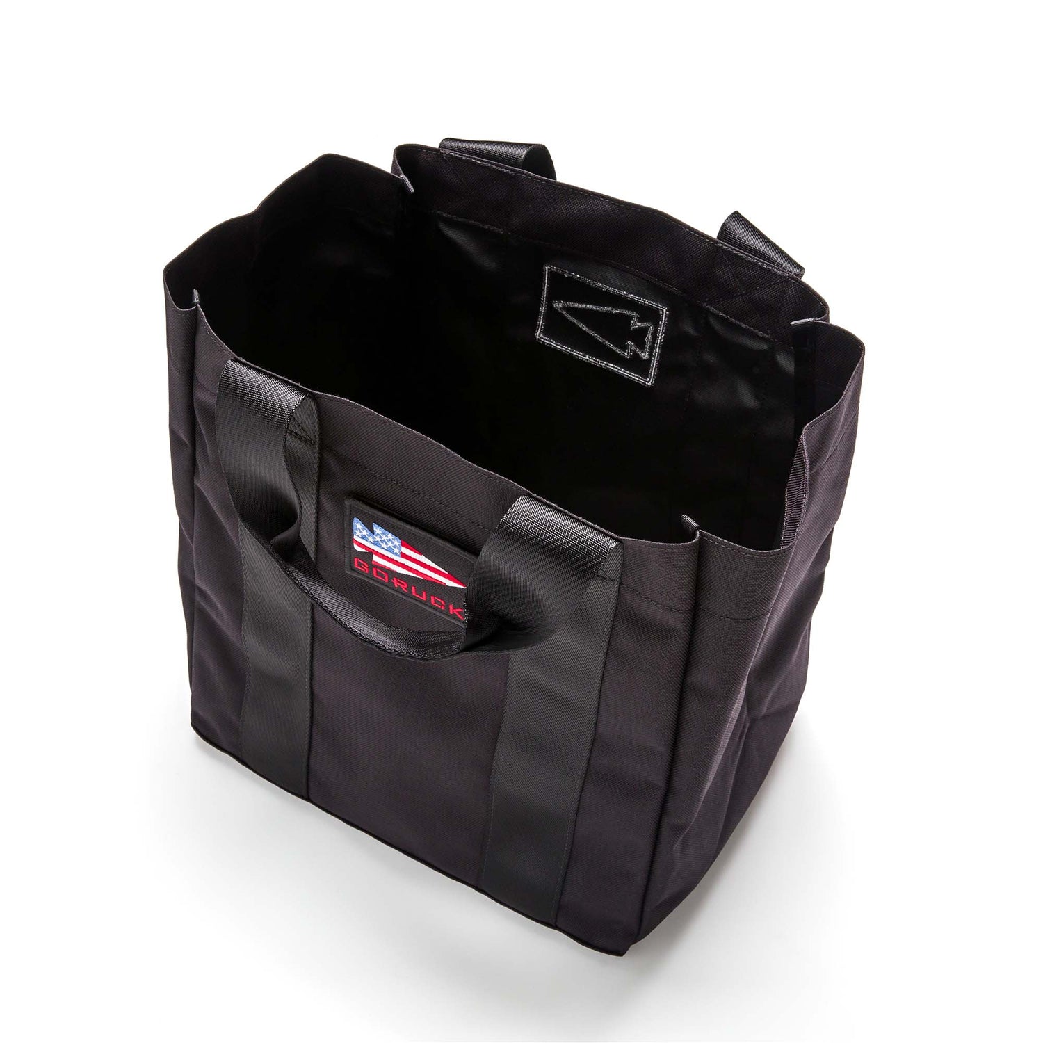The Grocery Getter is a black all-purpose tote with short handles and a front patch, made from durable 1000D Cordura, shown from above on a white background.