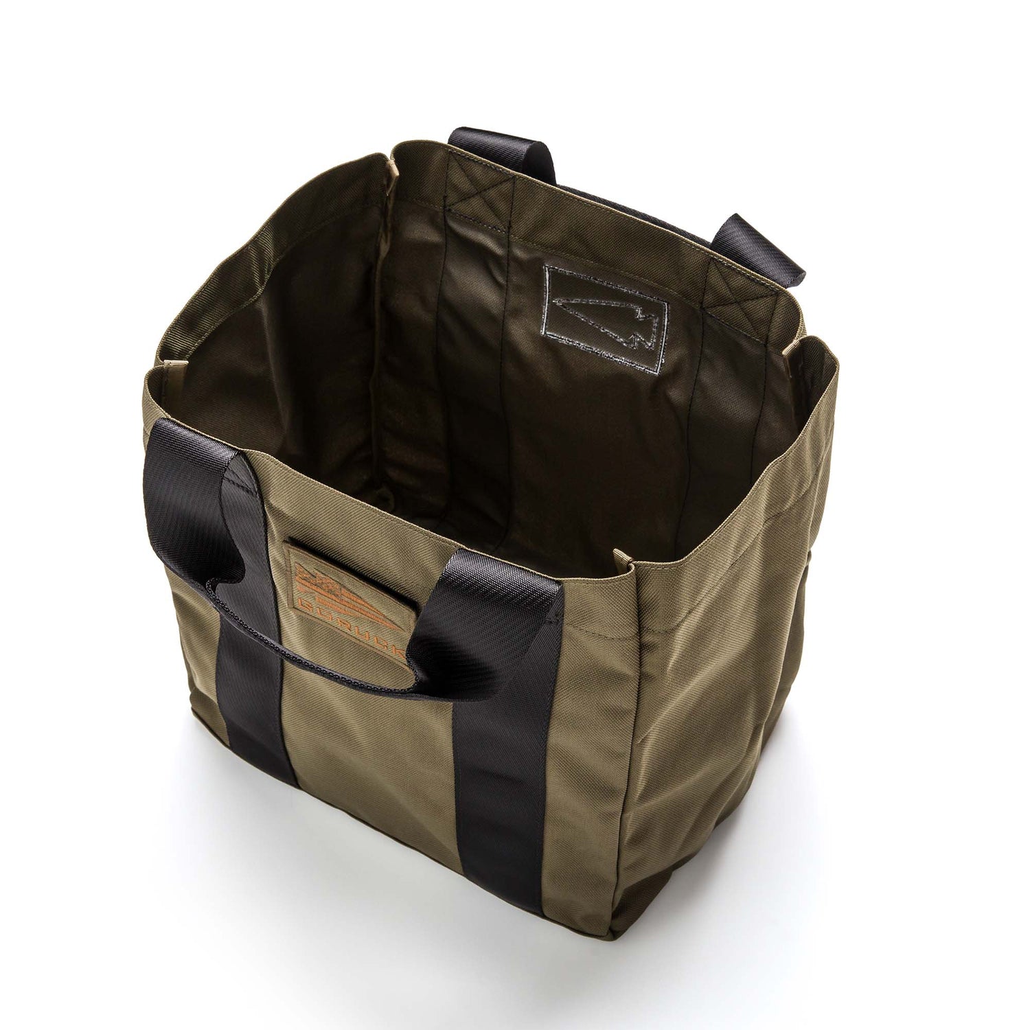 The olive green GORUCK Grocery Getter tote bag, made from rugged 1000D Cordura with black handles, is open and empty on a white background.