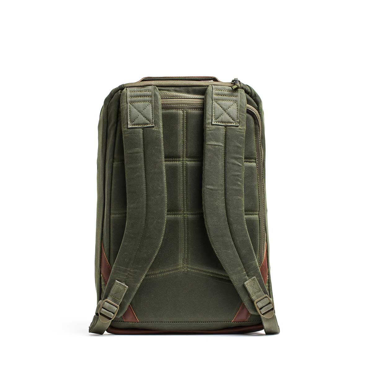 The GR1 USA - Heritage Waxed Canvas backpack in olive green is shown from the back, with padded straps, brown leather accents, and classic waxed canvas rucksack styling.