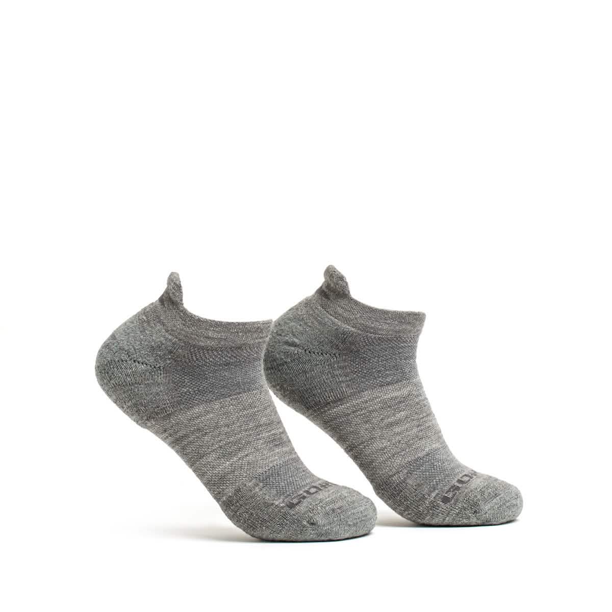 The Merino Challenge Socks - Ankle by GORUCK are showcased against a simple white backdrop. The gray wool socks stand upright, highlighting their subtle texture with a slightly darker heel and toe area, designed to excel in comfort.