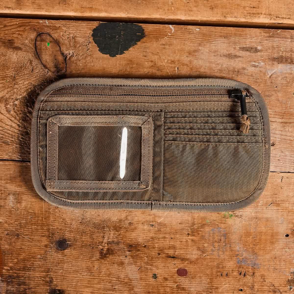 GORUCK coyote brown ID card organizer with clear ID window, card slots, and zippered pocket on wooden surface