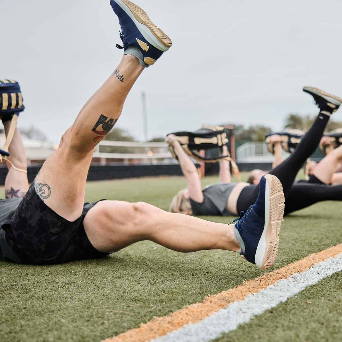 Group rucking workout on turf field with GORUCK gear and athletic shoes