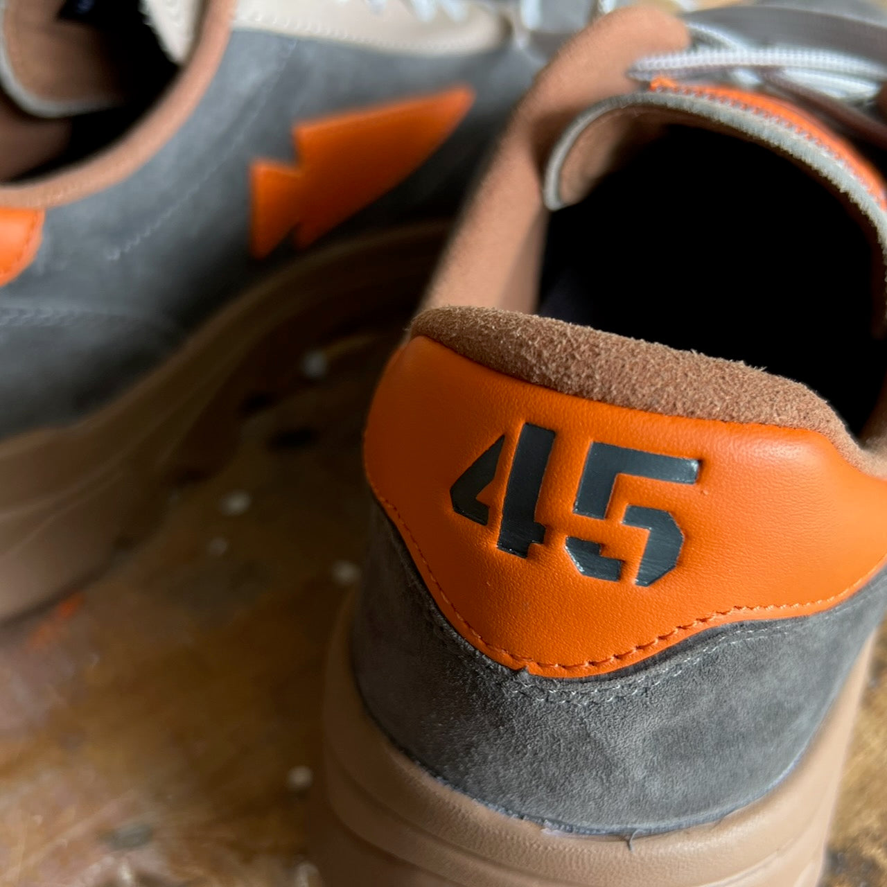 Close-up of the Mackall 45 Fog sneakers in gray and orange, featuring the number 45 on the heel and a lightning bolt design on the side.