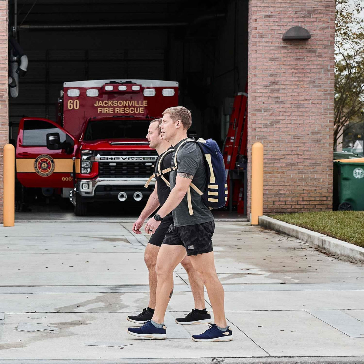 Two men rucking with GORUCK backpacks outside Jacksonville Fire Rescue station