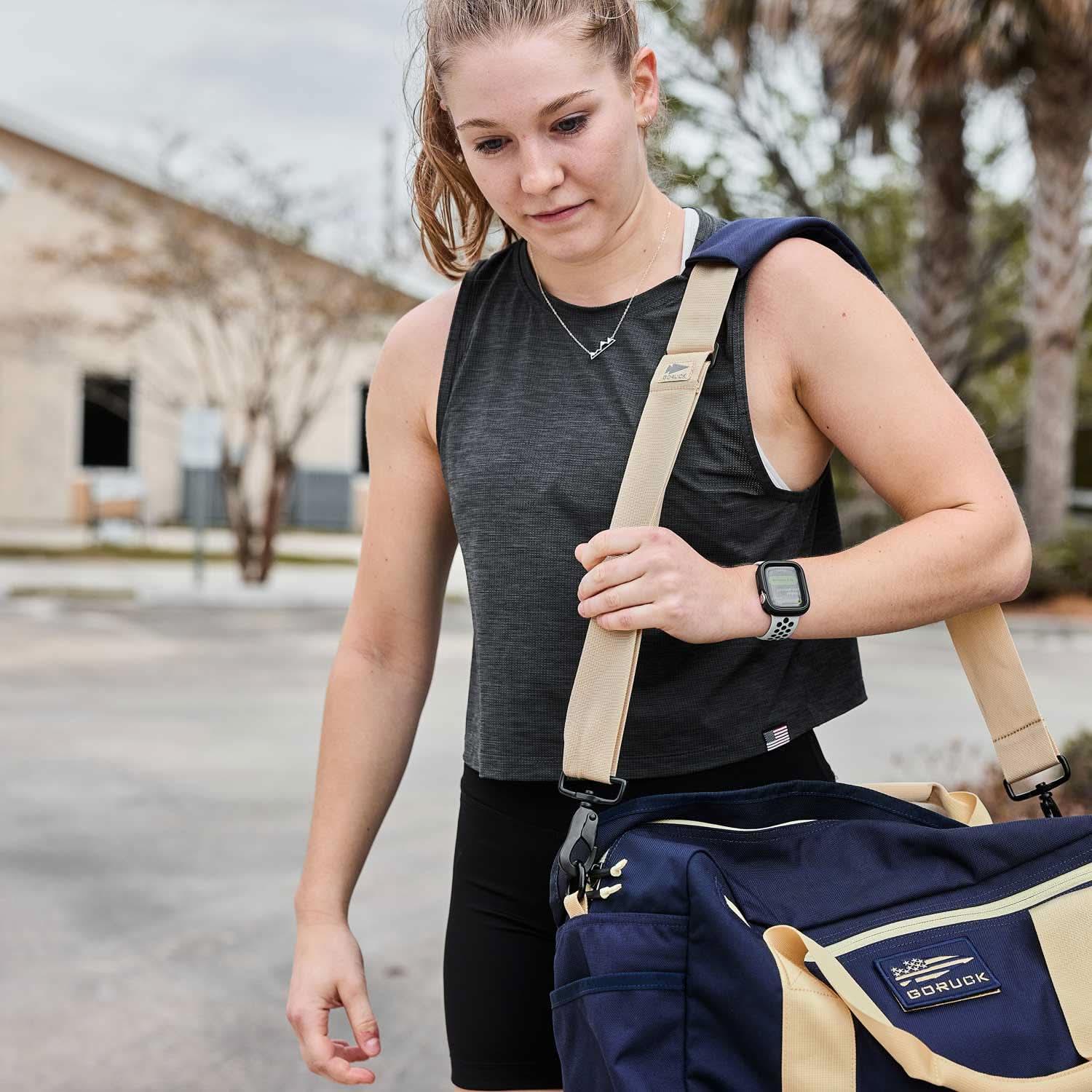 Woman carrying GORUCK gym gear bag outdoors, athletic wear, fitness lifestyle
