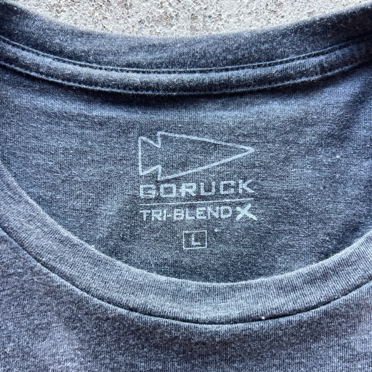 Close-up of the Embrace the Suck Tee - Tri-BlendX in gray, size L, featuring