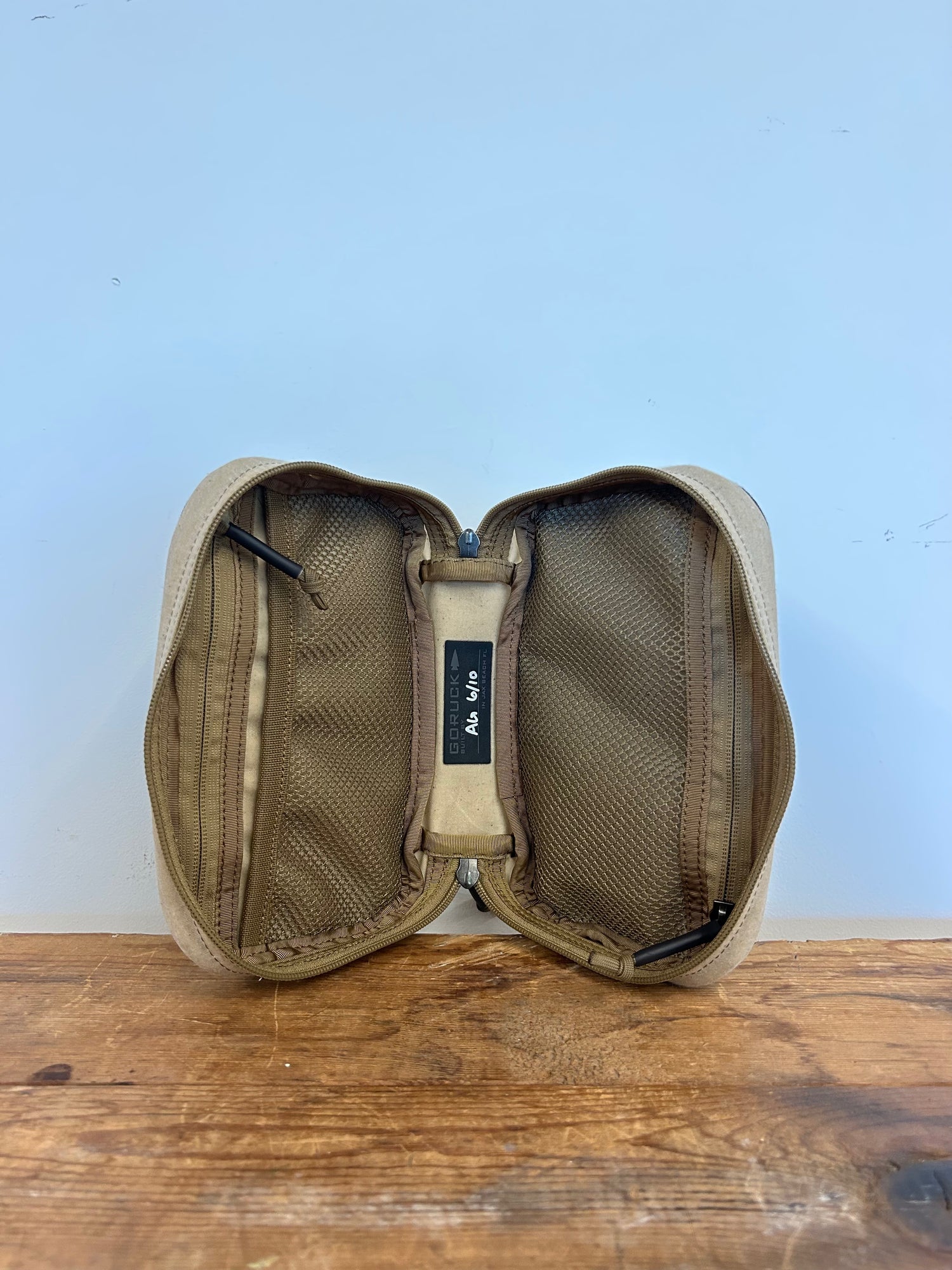 GORUCK tan zippered pouch open with mesh pockets on wooden surface