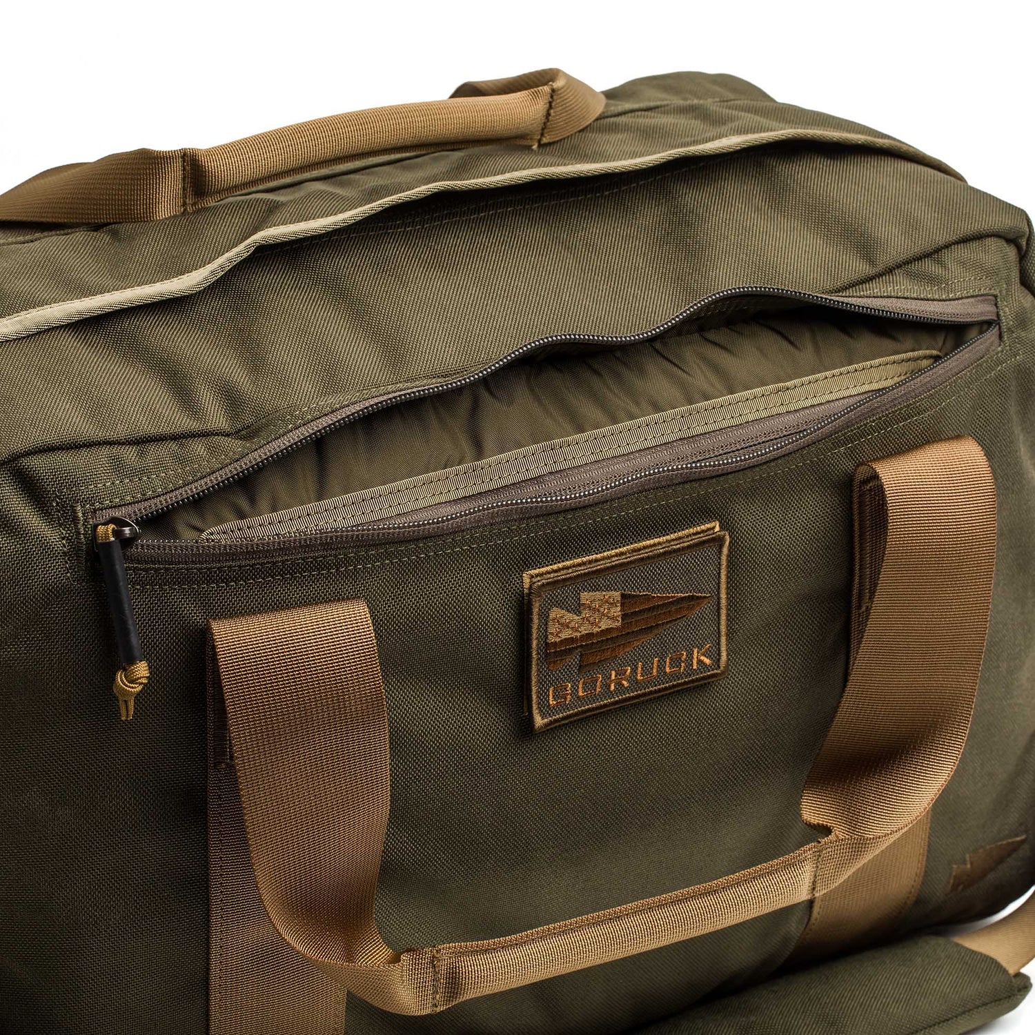 The Kit Bag (Includes Shoulder Strap) is an olive green and tan duffel inspired by a classic aviator’s kit bag, featuring a zippered front pocket and a GORUCK patch.