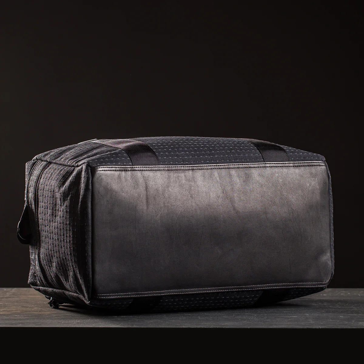 Black GORUCK kit bag with reinforced bottom panel on dark surface and black background