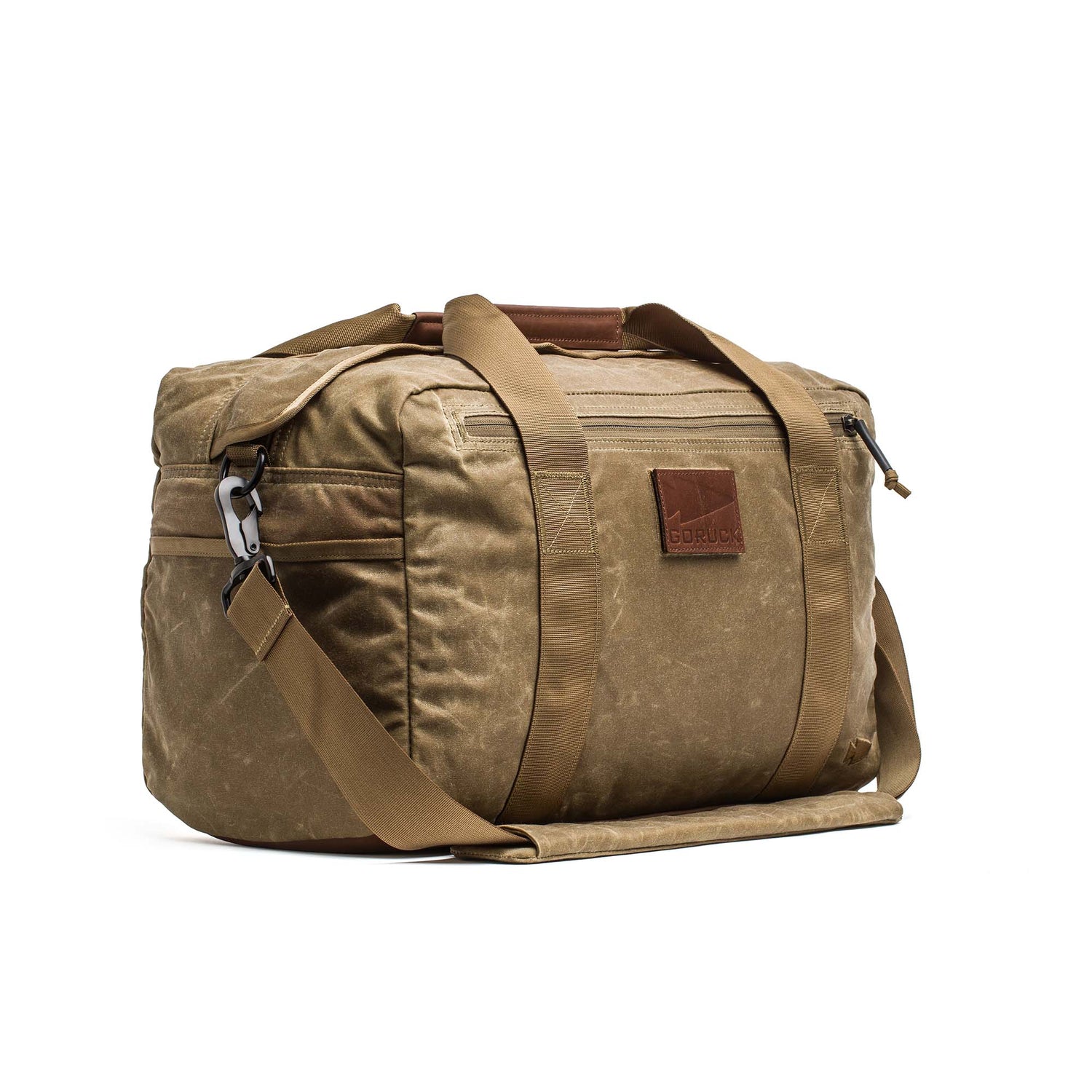 The Kit Bag - Waxed Canvas features a brown waxed canvas body with tan handles and a shoulder strap, styled like an aviator’s kit bag, shown against a white background.
