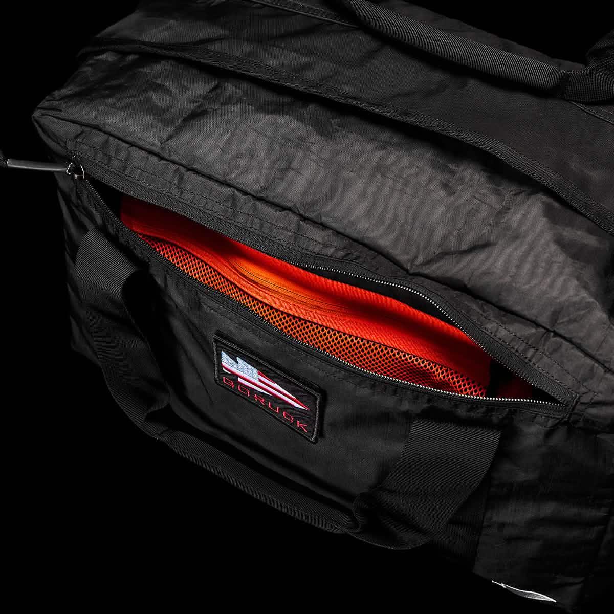 GORUCK black Dyneema kit bag with open zipper, orange interior and branded patch