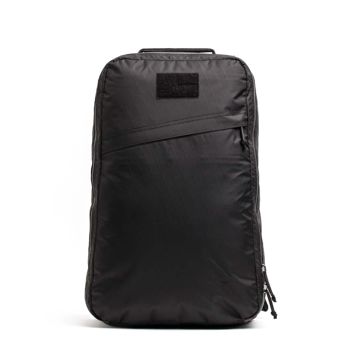 Front view of a sleek black GORUCK rucksack with diagonal zipper and handle on white background